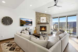 Living room featuring ceiling fan, a fireplace, wood finished floors, lofted ceiling, and recessed lighting