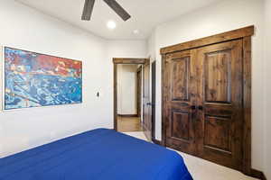 Bedroom with ceiling fan, light colored carpet, and a closet