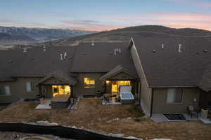Rear view of property with a hot tub, a patio, and a mountain view