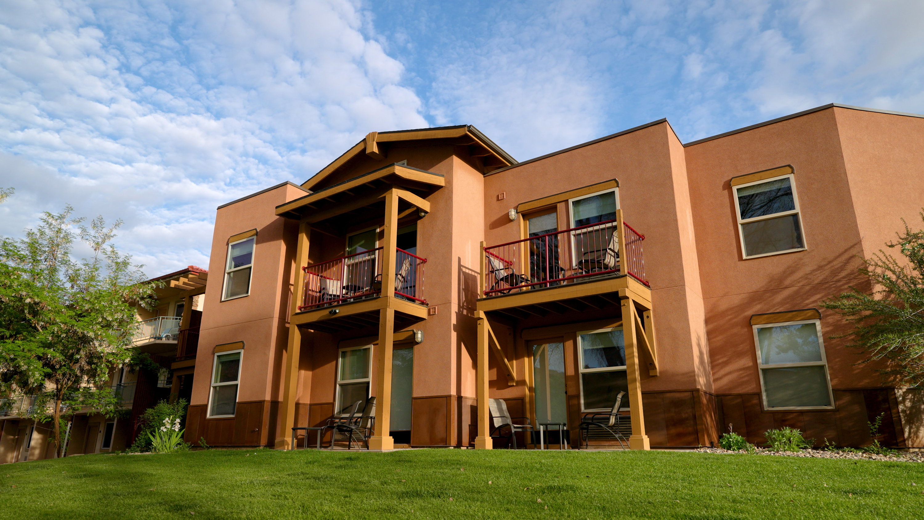 Back of house with a patio area, a balcony, stucco siding, and a lawn