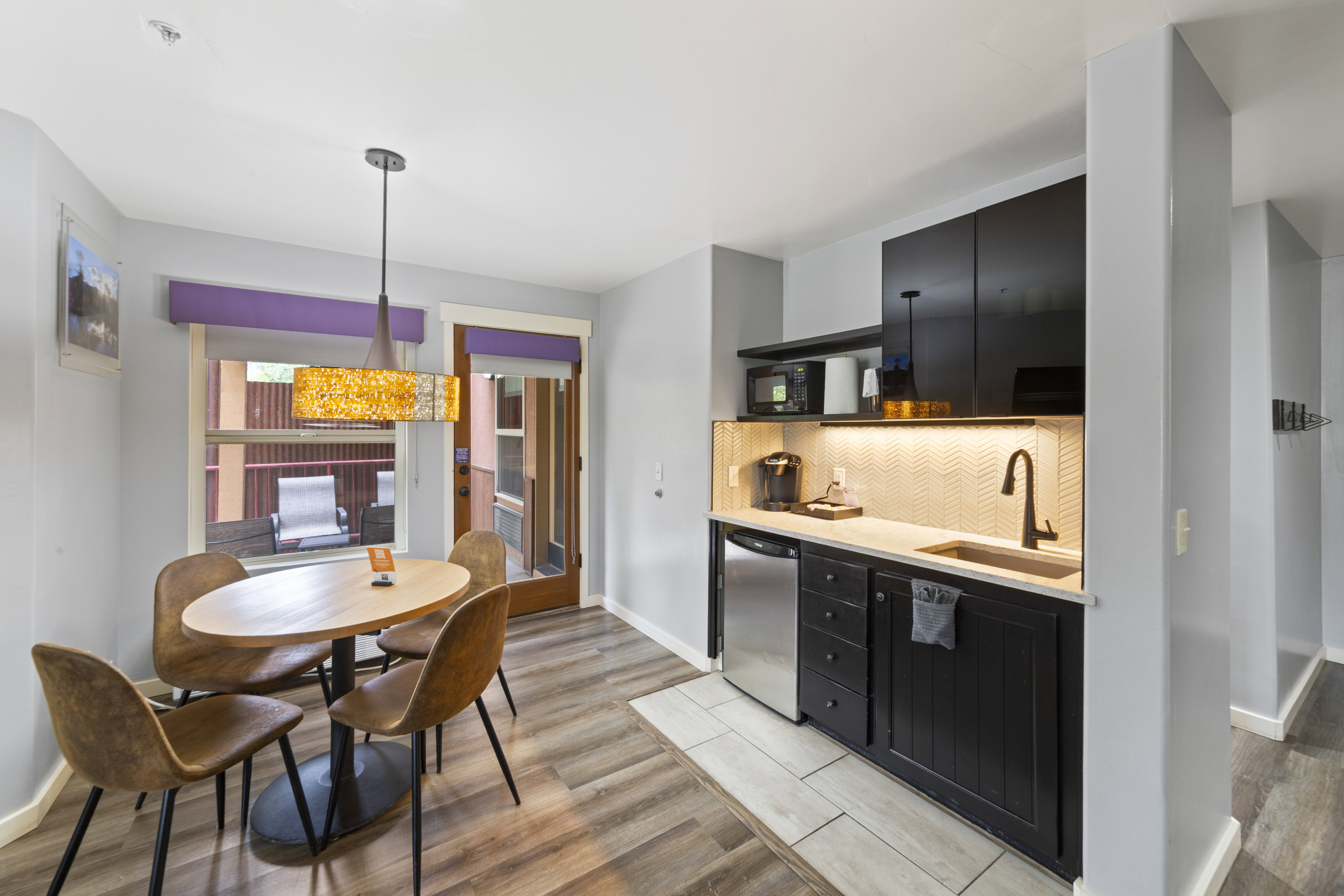 Kitchen with dark cabinets, light wood finished floors, backsplash, and dishwasher