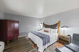 Bedroom with dark wood finished floors and baseboards
