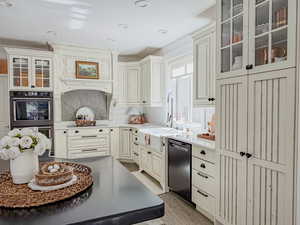 Kitchen with glass fronted cabinets, double oven, dishwasher, light wood-type flooring, and light stone countertops