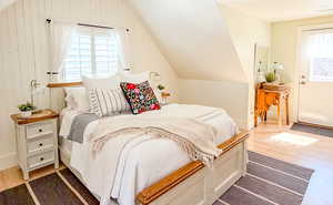 Bedroom featuring wood finished floors, lofted ceiling, and multiple windows