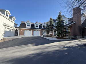Cape cod-style house with driveway, brick siding, and a garage