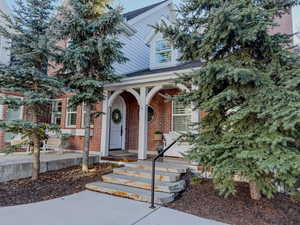 Entrance to property with a shingled roof, a porch, and brick siding