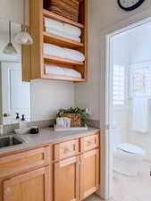 Kitchen with light wood finish cabinets, pendant lighting, open shelves, light tile patterned flooring, and light stone countertops