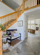 Stairs with stone finish flooring, a high ceiling, and a glass covered fireplace