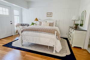 Bedroom with light wood-style floors, access to outside, and wood walls