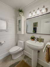 Half bath with wood walls and concrete flooring