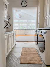 Laundry room with cabinet space, washing machine and dryer, lofted ceiling, and light wood-style flooring