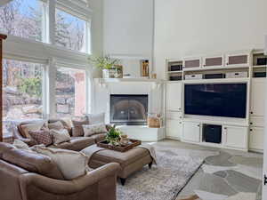 Living area with a high ceiling, light stone finish flooring, and a fireplace