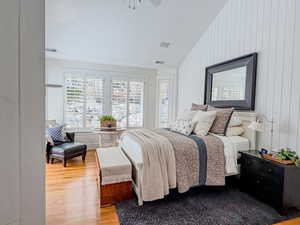 Master Bedroom with light wood-type flooring, vaulted ceiling, a ceiling fan, and wooden walls
