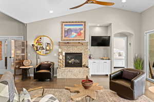 Living area with lofted ceiling, a fireplace, wood finished floors, a ceiling fan, and recessed lighting