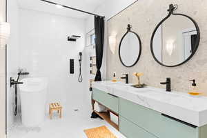 Bathroom with double vanity, tile walls, a freestanding bath, and tiled shower