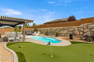 View of pool with an area to practice putting, a pergola, patio surround, and a fenced backyard