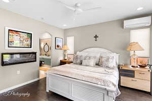 Bedroom featuring dark wood-style floors, recessed lighting, a ceiling fan, connected bathroom, and arched walkways