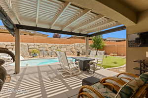 Fenced backyard with a pergola, a putting area, and a patio