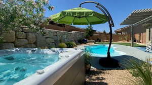 View of swimming pool featuring patio surround, a pergola, a fenced backyard, and a hot tub