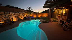 View of pool featuring patio surround, a fenced backyard, and a pergola