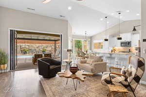 Living area with light wood-type flooring, a high ceiling, hanging lights, and a ceiling fan