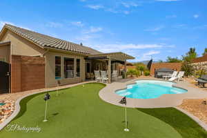 View of swimming pool featuring a putting green, patio surround, and a fenced backyard