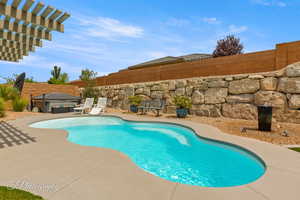 View of swimming pool featuring patio surround, a fenced backyard, and a pergola
