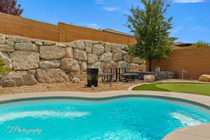 View of pool featuring patio surround, a fenced backyard, and a putting green