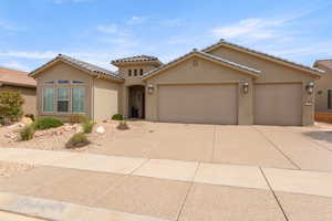Mediterranean / spanish home with an attached garage, driveway, stucco siding, and a tile roof