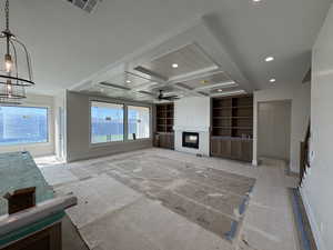 Unfurnished living room with a glass covered fireplace, ceiling fan, coffered ceiling, recessed lighting, and built in features