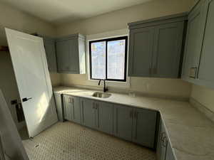 Kitchen featuring a sink and light stone counters