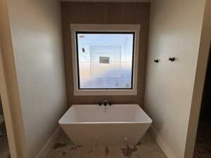 Full bath with a soaking tub and baseboards