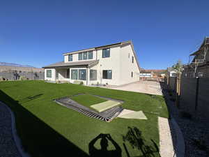 Rear view of house with stucco siding, a fenced backyard, a mountain view, and a patio area