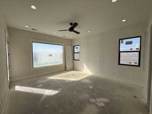 Unfurnished room featuring unfinished concrete floors, a ceiling fan, plenty of natural light, and recessed lighting