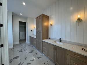 Bathroom featuring two vanities, a spacious closet, and recessed lighting