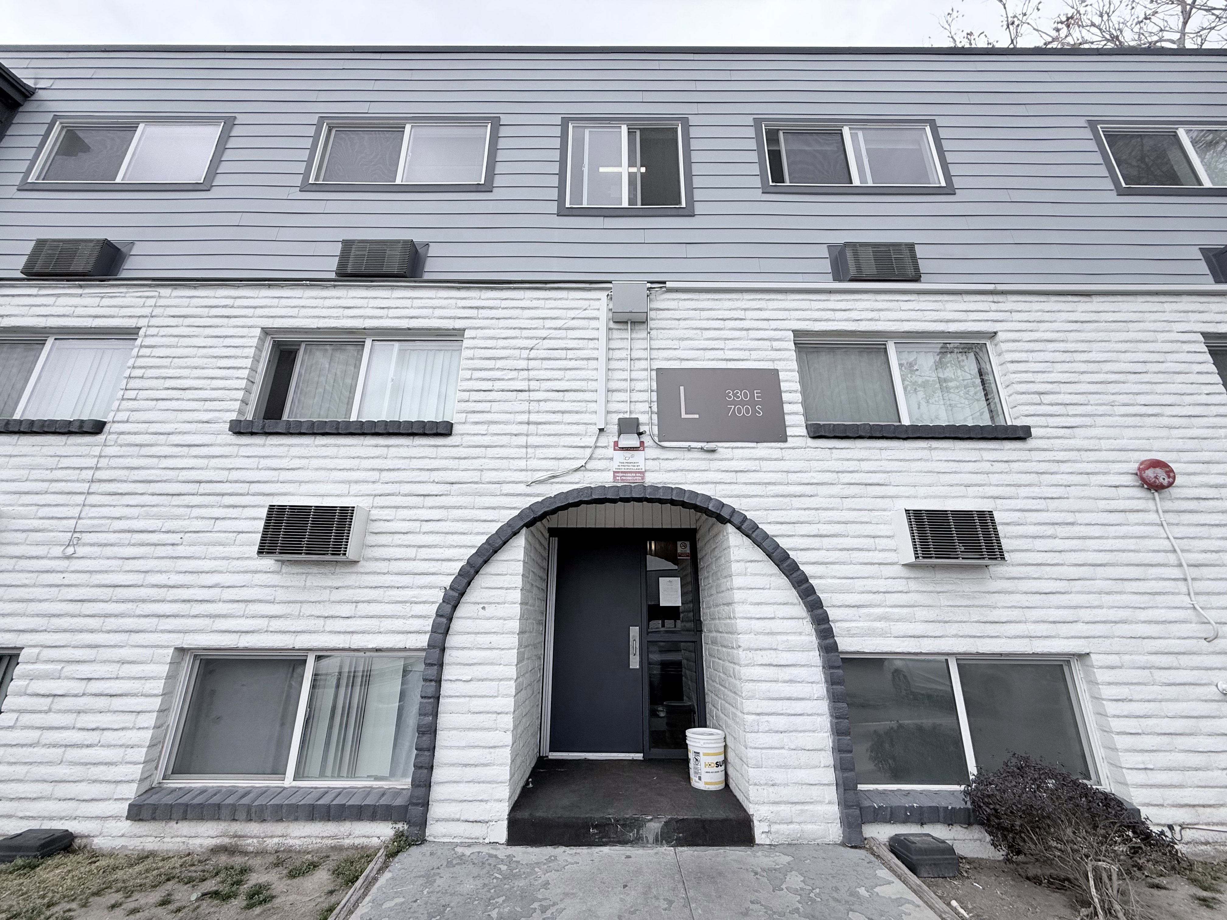 Multi-level building exterior featuring white brick and gray siding