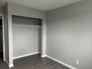 Unfurnished bedroom featuring dark wood-style flooring and a closet