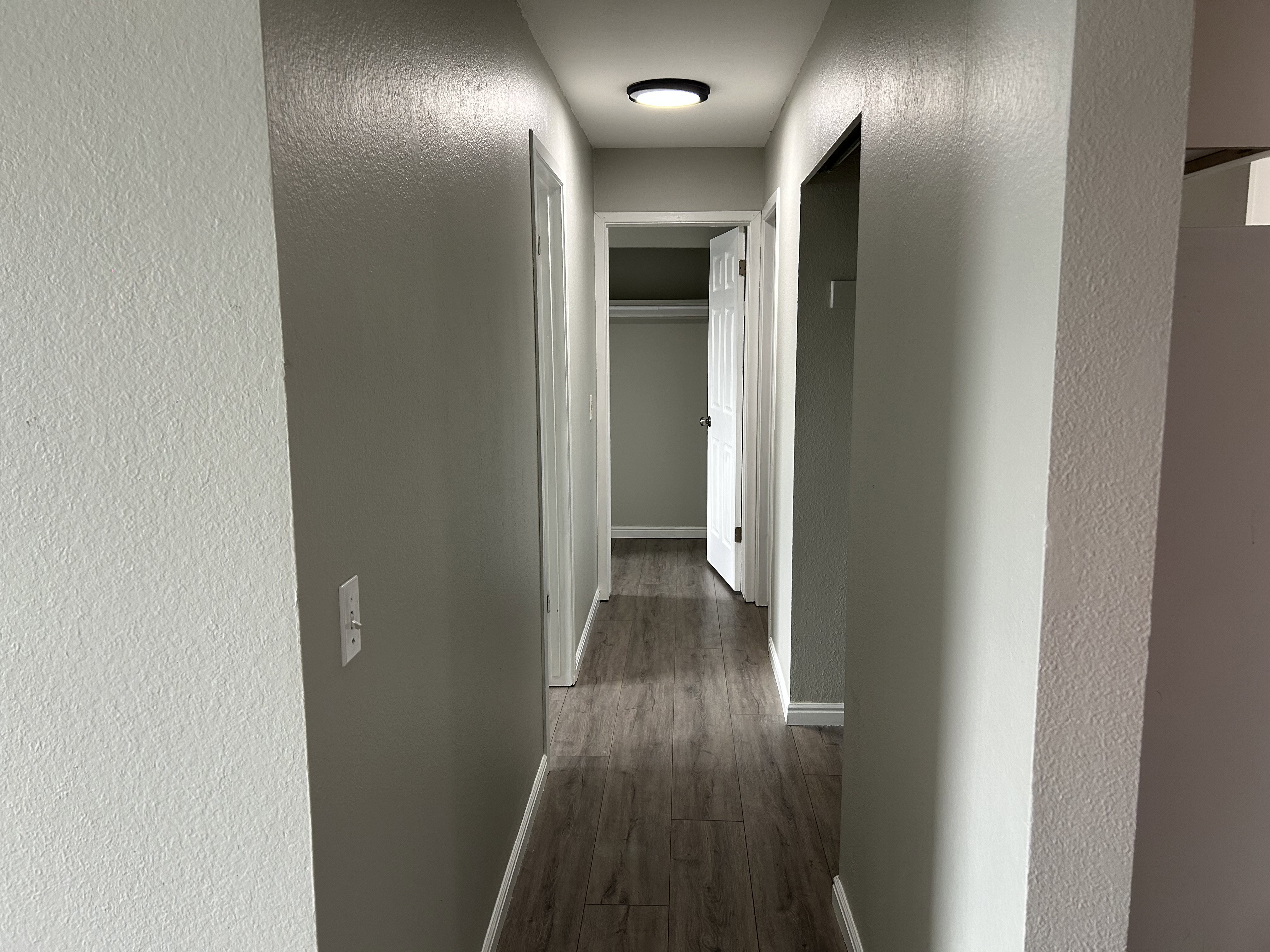 Corridor with a textured wall and dark wood-style floors