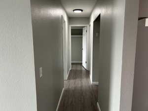 Corridor with a textured wall and dark wood-style floors