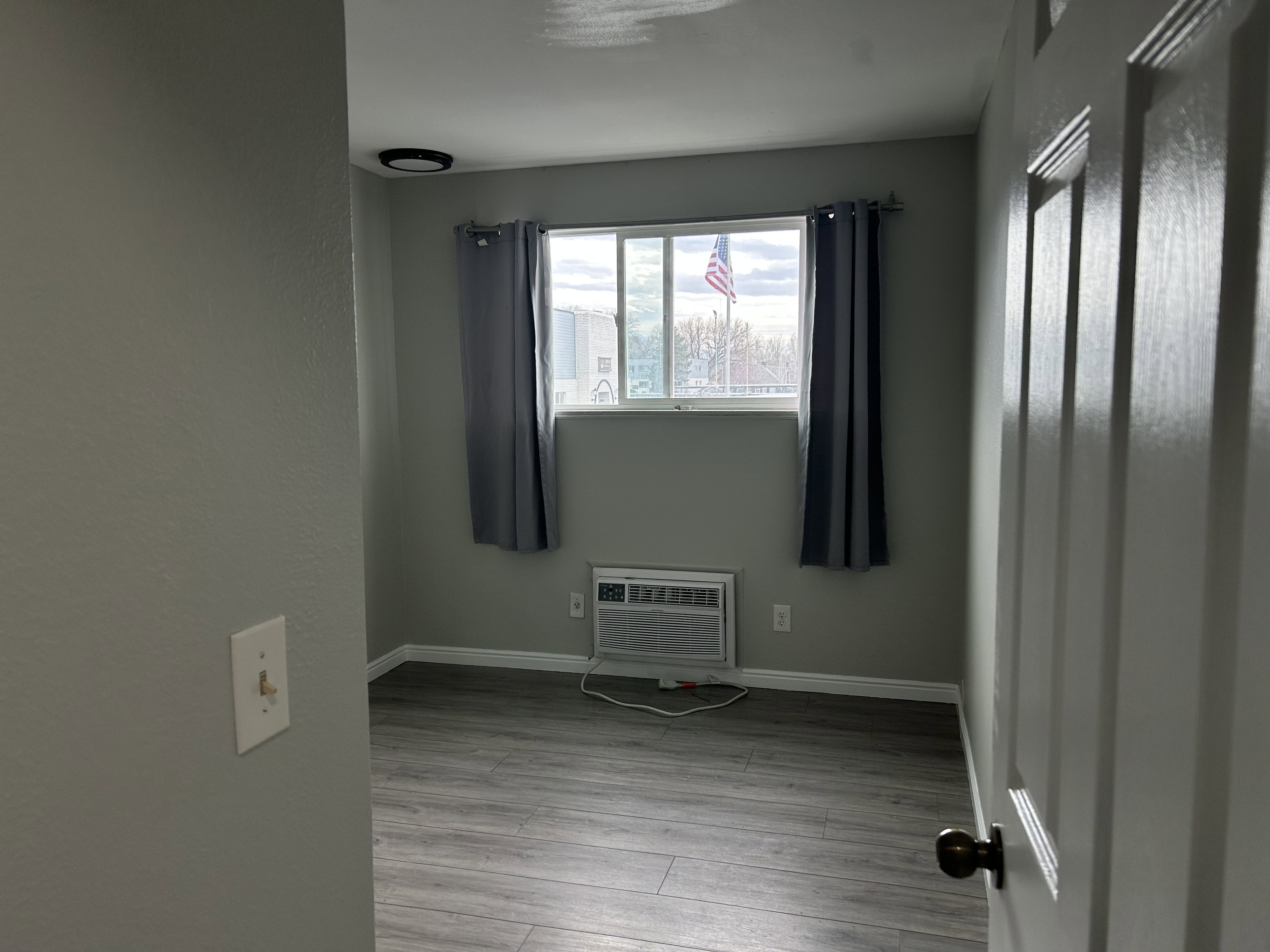 Empty room featuring light wood-style floors and a wall mounted air conditioner