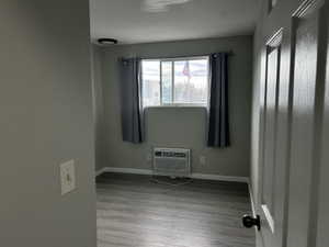Empty room featuring light wood-style floors and a wall mounted air conditioner