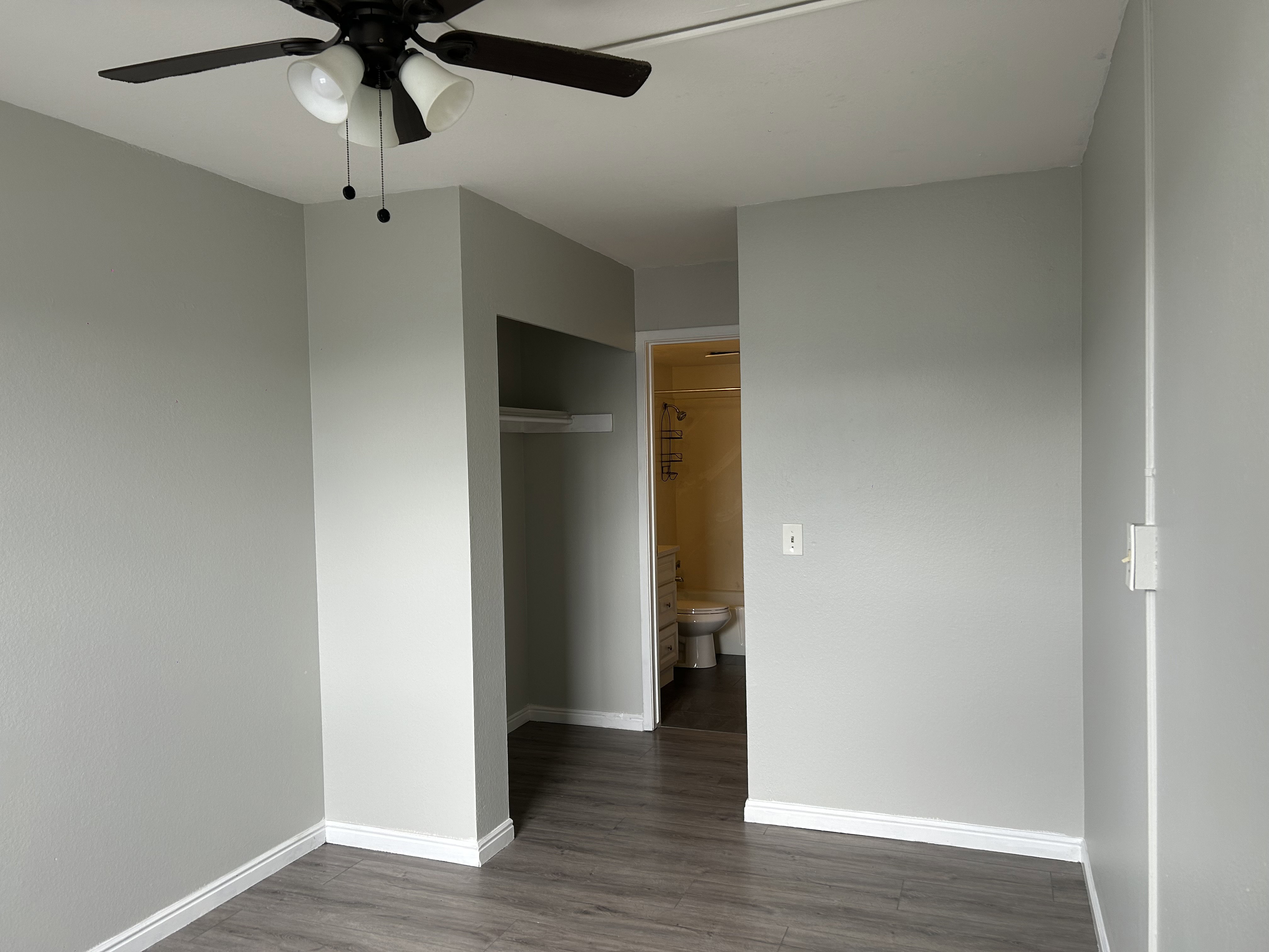 Unfurnished bedroom with a closet, dark wood-type flooring, and a ceiling fan