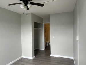 Unfurnished bedroom with a closet, dark wood-type flooring, and a ceiling fan