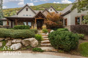 View of front of house with stone siding, a porch, and stucco siding