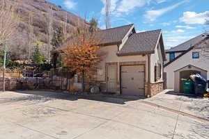 View of front of house with driveway, stone siding, a garage, and stucco siding