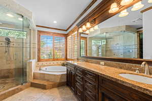 Bathroom featuring double vanity, a shower stall, stone tile flooring, a bath, and crown molding