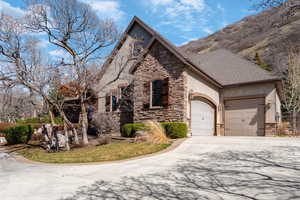 View of front of house featuring stone siding, concrete driveway, an attached garage, stucco siding, and a shingled roof