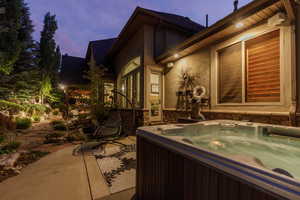 View of side of home with a hot tub, stucco siding, and a patio area
