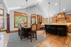 Dining room featuring light wood-style flooring, vaulted ceiling, and suspended lighting