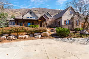View of front of property featuring stone siding, stucco siding, and covered porch